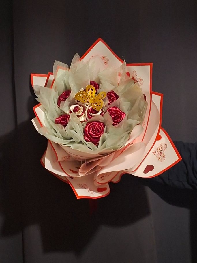 Bouquet Roses avec papillon ; Bouquet de fleurs avec des roses rouges et des décorations dorées, entouré de feuilles. Bouquet de fleurs avec des roses rouges et des décorations dorées, entouré de feuilles.